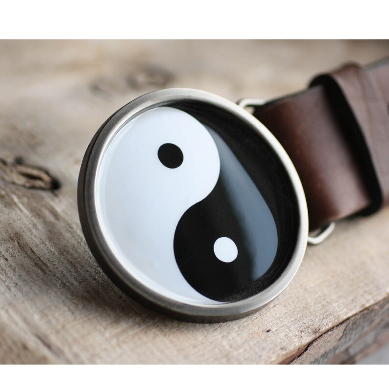 May include: A silver belt buckle with a black and white yin yang symbol.