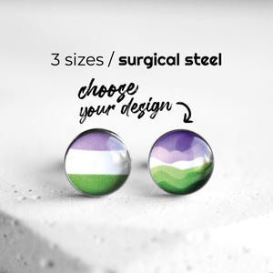 Puede incluir: Dos pendientes de botón redondos con un diseño de la bandera del orgullo genderqueer. Los pendientes presentan una combinación de colores púrpura, blanco y verde. El texto dice "3 tamaños / acero quirúrgico" y "elige tu diseño".