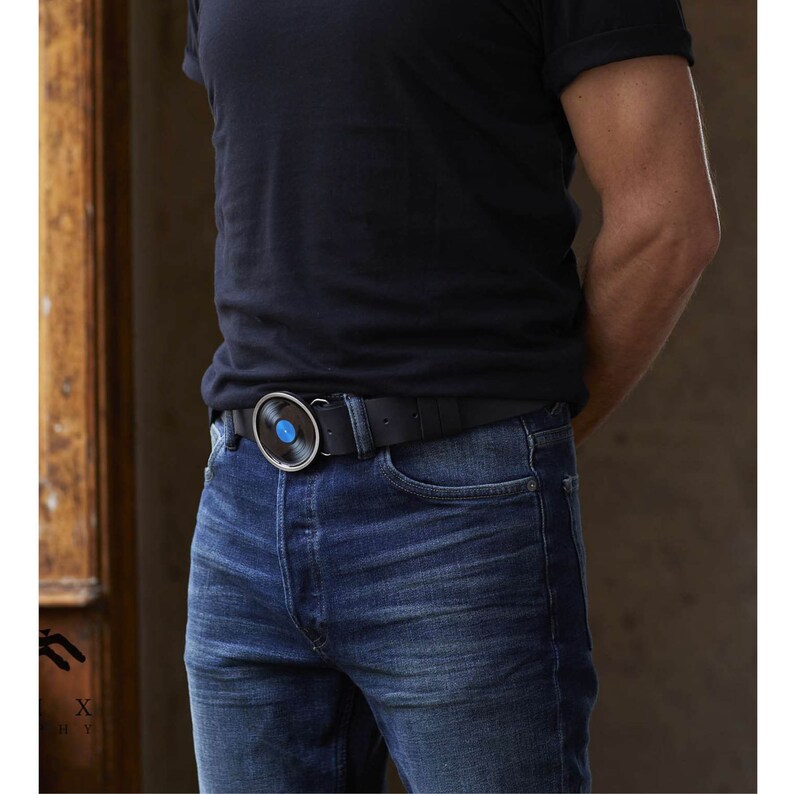 May include: A black leather belt with a silver buckle featuring a black vinyl record with a blue center.