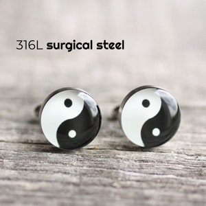 May include: A pair of silver cufflinks with a black and white yin yang symbol design. The cufflinks are made of 316L surgical steel.