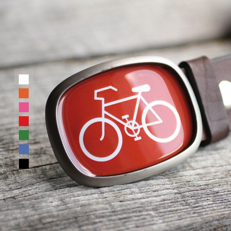 May include: A silver belt buckle with a red background and a white silhouette of a bicycle.