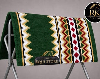 Op de afbeelding: Een groene zadeldek met een geometrisch patroon in wit, goud, rood en zwart. De pad wordt op een metalen standaard getoond. Het Equi Store-logo is zichtbaar.