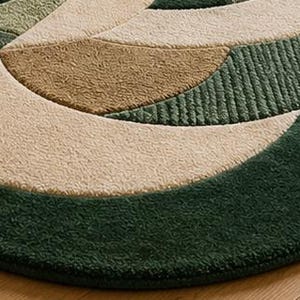 K&ouml;nnte beinhalten: Ein getufteter Teppich mit geschwungenem, wellenf&ouml;rmigem Randdesign in den Farben Waldgr&uuml;n, Olivgr&uuml;n und Beige. Die Oberfl&auml;che zeigt eine Mischung aus dichtem, glattem Flor und strukturierten, gerippten Abschnitten in kreisf&ouml;rmigen Mustern.