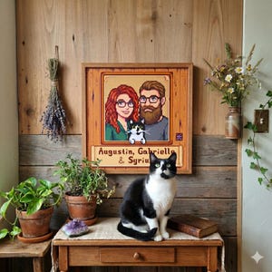 Puede incluir: Un retrato pixelado enmarcado de una pareja y un gato, con los nombres "Augustin, Gabriella & Syriu" debajo. Un gato blanco y negro est&aacute; sentado en una mesa de madera frente al retrato. La mesa tiene un caj&oacute;n y un libro peque&ntilde;o.
