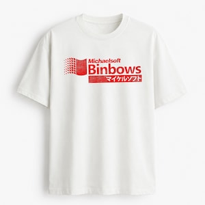 Może przedstawiać: Biały t-shirt z krótkim rękawem i czerwoną grafiką na klatce piersiowej. Nadruk przedstawia napis Michaelsoft Binbows o postarzanym wyglądzie, ikonę flagi złożoną z małych kwadratów oraz japoński tekst umieszczony w czerwonym prostokątnym polu.