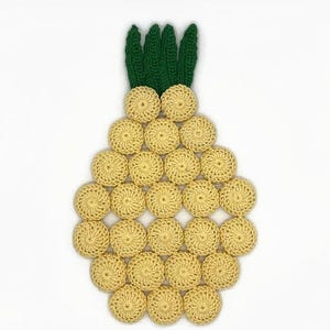 May include: A pineapple-shaped trivet made of interconnected yellow crocheted circles forming the body and dark green crocheted leaves at the top. The design features a repeating circular pattern with open spaces between the yellow yarn segments.