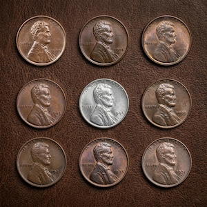 Puede incluir: Una colección de nueve monedas de un centavo de los Estados Unidos dispuestas en una cuadrícula de tres por tres. Ocho monedas son de color cobre con las fechas 1909, 1914, 1909, 1943, 1955, 1922, 1935 y 1931. Una moneda central es plateada y data de 1944.