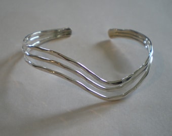 May include: A silver bracelet with three wavy bands.