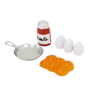 May include: A miniature set featuring a silver-colored metal frying pan, a small red jar with a white label reading Beets, three smooth white oval-shaped eggs, and a cluster of six connected orange-colored food items with a glossy finish.