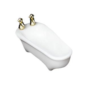 May include: A miniature white ceramic bathtub featuring two gold-colored faucet handles at one end. The tub has a smooth, glossy finish and is shaped with a rounded rim and four small feet at the base, presented from a high-angle perspective.