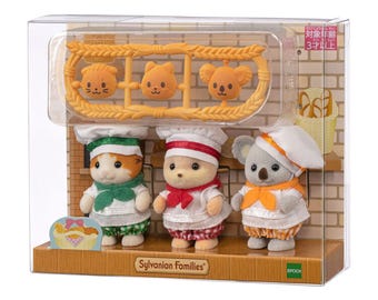 May include: Three Sylvanian Families animal figures dressed as bakers in a clear plastic box. The set includes a cat, a bear, and a koala wearing chef hats and aprons, with a plastic frame containing three small bread-shaped accessories above them.