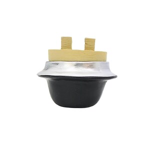 May include: A decorative bottle stopper. It features a black base, a silver-coloured midsection, a light tan band, and two small, textured tan pieces on top. Designed to fit into a bottle.