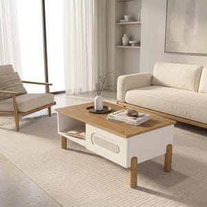 May include: A modern coffee table with a light wood top and white base. The table has a lower shelf and a decorative panel on the side. A tray with a vase and books are on top. The table is supported by four wooden legs.