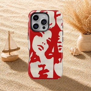 May include: A smartphone case featuring a high-contrast, two-tone graphic design in bold red and off-white. The pattern consists of abstract, stylized facial features and shapes that repeat across the surface of the protective cover.