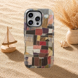 Könnte beinhalten: Eine Smartphone-Hülle mit einem Patchwork-Design aus verschiedenen Stoffquadraten in gedeckten Braun-, Rot-, Blau- und Cremetönen. Das Muster besteht aus einfarbigen Flächen, Karos und kleinen Punkten, die alle mit sichtbarem Garn vernäht sind.