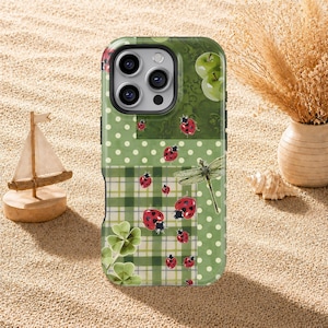 Puede incluir: Funda de teléfono con estampado verde y blanco con mariquitas, una libélula y manzanas. La funda tiene un diseño de patchwork con lunares, cuadros y elementos florales. Las mariquitas son rojas con puntos negros.