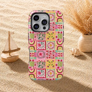 Könnte beinhalten: Eine bunte Handyhülle mit einem Patchwork-Design mit floralen und geometrischen Mustern in Rosa, Gelb, Grün und Rot. Die Hülle hat einen schwarzen Rand und einen Kameraausschnitt.