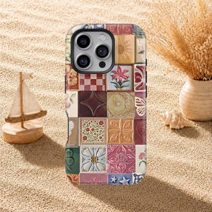 Pode incluir: Capa de telefone colorida com um design de patchwork de ladrilhos quadrados. Os ladrilhos exibem padrões florais, geométricos e celestiais em tons de rosa, azul, amarelo e marrom. A capa tem uma borda preta e um recorte para a câmera.