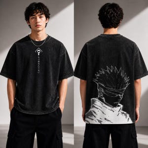 May include: Black, oversized t-shirt with a faded wash effect. The front features a white graphic and Japanese text. The back displays a large black and white illustration of a character with spiky hair and a blindfold.