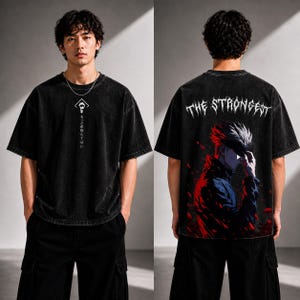 May include: Black oversized t-shirt with a graphic on the front and back. The front features a white symbol and Japanese text. The back displays an anime character with the text "THE STRONGEST" in white.