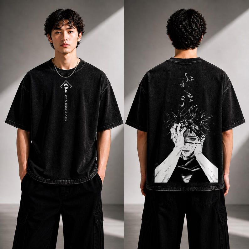 May include: Black oversized t-shirt with a distressed wash. The front features a white graphic and Japanese text. The back displays a detailed black and white illustration of a character with hands on their head. The model is wearing black cargo pants.