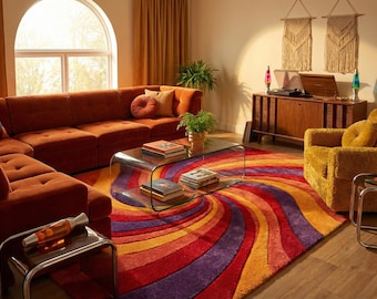 May include: A retro-style living room with a large rust-colored sectional sofa, a patterned rug in shades of red, orange, yellow, and purple, and a glass coffee table. The room is decorated with macrame wall hangings and a vintage stereo.