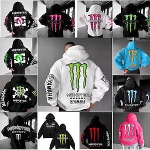 May include: Assortment of hooded sweatshirts featuring the Monster Energy logo in various colors, including black, white, and pink. Designs include the Monster claw mark and text. The sweatshirts have long sleeves and a casual style.