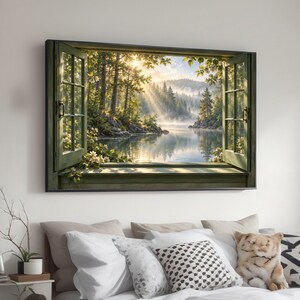 May include: A rectangular wall art print featuring an open window frame looking out onto a serene lake surrounded by a dense forest. Sunlight streams through the trees, creating rays of light over the water, with white flowers on the window sill.