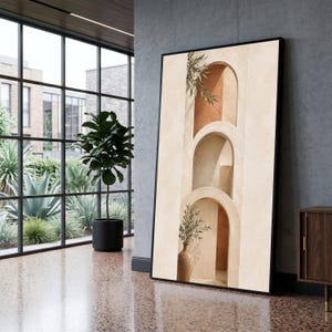 Può includere: Una stampa artistica da parete rettangolare verticale in una cornice nera che presenta una serie di tre archi in pietra beige sovrapposti. L'opera mostra una parete interna color terracotta e un vaso in ceramica con rami verdi.