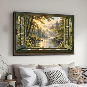 May include: A rectangular wall art print featuring an open window frame looking out onto a sunlit forest landscape with a river, green trees, and golden light rays filtering through the foliage, framed in a dark wooden border.