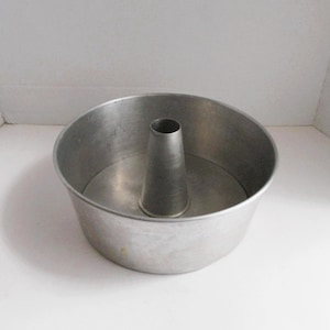 May include: A silver metal bundt cake pan with a removable center tube. The pan is designed for baking cakes with a hole in the center.