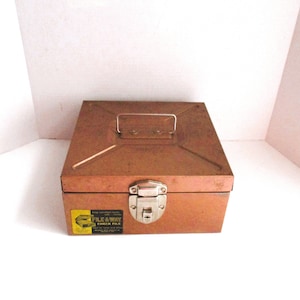 May include: A vintage metal File-Away Check File box with a brown finish and a silver latch. The box has a handle on the top and a label that reads "File-Away Check File".
