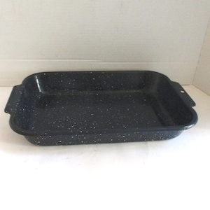 May include: A rectangular baking pan with a black enamel finish and white speckled details. The pan features integrated handles on both short ends, with a small circular hole on one handle, and has a smooth, glossy surface throughout the interior.