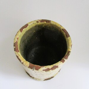 May include: A white ceramic planter with a brown rim. The planter has a distressed look with brown and yellow paint.