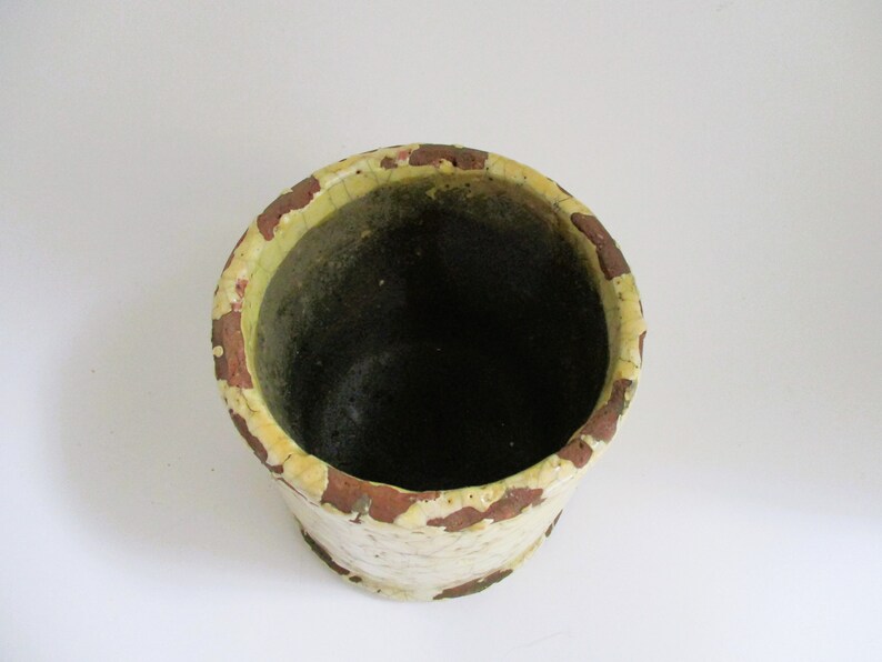May include: A white ceramic planter with a brown rim. The planter has a distressed look with brown and yellow paint.