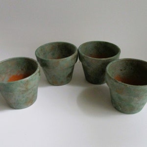 May include: Four small terracotta pots with a green and brown speckled glaze. The pots are unglazed on the inside.