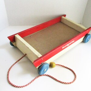 May include: A vintage wooden toy wagon with a red and white striped pull cord. The wagon has a red rim, cream-colored sides, and blue wheels. The word "holgate" is printed on the side.