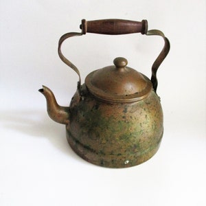May include: A vintage copper kettle with a wooden handle. The kettle has a green patina and is in good condition.