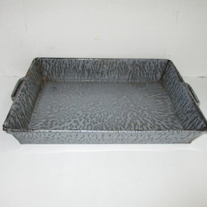 May include: A gray enamel baking pan with a speckled pattern and two handles. The pan is rectangular and has a slightly rounded edge.