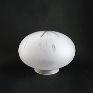 May include: Frosted glass lampshade with a rounded, oval shape. The lampshade has a small, circular base and is decorated with etched floral designs. The glass is opaque, and the overall appearance is soft and diffused.