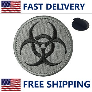 May include: A round, gray patch with a black biohazard symbol in the center. The patch has a stitched border and the words "FAST DELIVERY" and "FREE SHIPPING" are displayed above and below the patch.