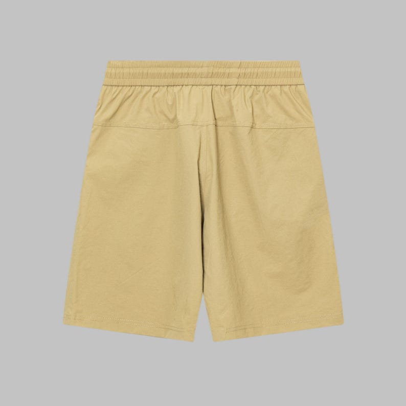 Pode incluir: Cal&ccedil;&otilde;es cor c&aacute;qui com c&oacute;s el&aacute;stico. Os cal&ccedil;&otilde;es t&ecirc;m um ajuste descontra&iacute;do e um design simples, adequados para uso casual. O tecido parece leve e ligeiramente texturizado.