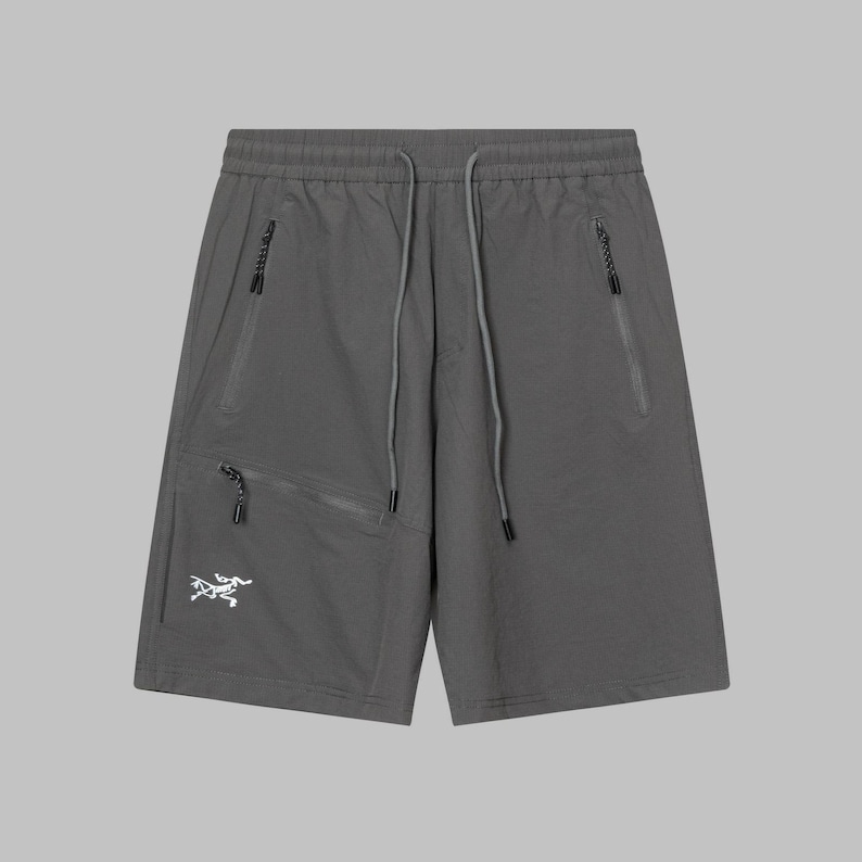 Pode incluir: Cal&ccedil;&otilde;es desportivos cinzentos com v&aacute;rios bolsos com z&iacute;per e cintura com cord&atilde;o. Os cal&ccedil;&otilde;es apresentam um log&oacute;tipo branco na perna esquerda. Feitos de um material leve e dur&aacute;vel. Perfeitos para desporto ou uso casual.