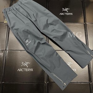 K&ouml;nnte beinhalten: Graue Arc'teryx-Regenhose mit elastischem Bund und Rei&szlig;verschlusstaschen. Die Hose hat das Arc'teryx-Logo auf dem linken Bein und Rei&szlig;verschl&uuml;sse an den Kn&ouml;cheln. Hergestellt aus leichtem, wasserdichtem Material.