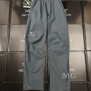 K&ouml;nnte beinhalten: Graue, wasserdichte Hose mit Arc'teryx-Logo. Die Hose hat einen elastischen Bund und Rei&szlig;verschl&uuml;sse an den Beinseiten. Hergestellt aus strapazierf&auml;higem, wasserdichtem Material.