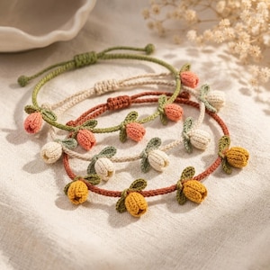 May include: Several handmade bracelets with crochet flower details. The bracelets are in various colors, including green, beige, orange, and yellow. The flowers are attached to the bracelet bands, which are adjustable.