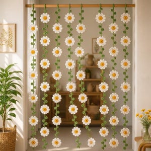 May include: A crochet daisy curtain with white petals and yellow centers, strung on green vines. The curtain hangs in a doorway, adding a touch of handmade charm to the room. The daisy curtain is a decorative home decor item.