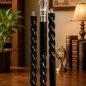 May include: A three-piece walking stick featuring a polished silver-tone handle with intricate engravings. The shaft consists of two black segments with a twisted spiral design and one smooth black segment, all connected by threaded metal screws.