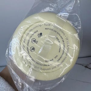 May include: A pale yellow water bottle base, sealed in a clear plastic bag. The base has printed text including "32oz/945mL" and "BPA FREE". The bottle is not for use with hot or carbonated liquids. Made in Vietnam.