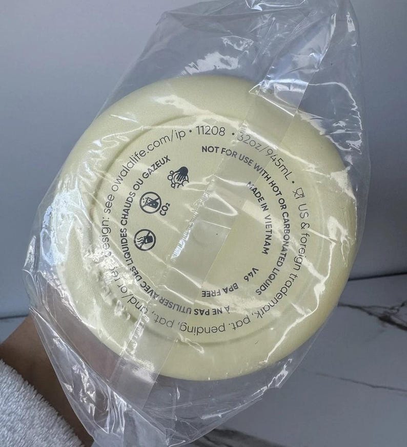 May include: A pale yellow water bottle base, sealed in a clear plastic bag. The base has printed text including "32oz/945mL" and "BPA FREE". The bottle is not for use with hot or carbonated liquids. Made in Vietnam.